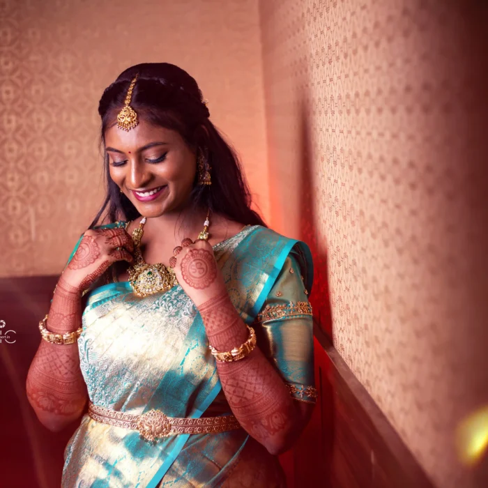 bridal photography poses 20 South Indian bride smiling and adjusting antique gold necklace in teal silk saree Tirunelveli Tamil Nadu